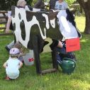 Kinder melken eine Holzkuh